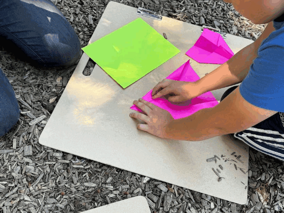 Kids folding bright paper at a miniLAB pop-up